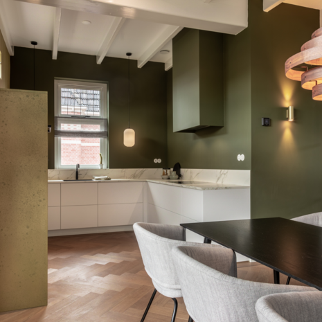 Wit bakeliet schakelmateriaal in moderne keuken met groene wanden en wit stalen deuren